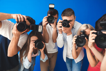 Group of young photographers on color background
