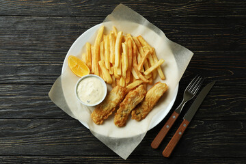 Plate with tasty fried fish and chips on wooden background