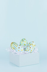 Simple and minimal easter background - easter eggs with golden design in gift box on blue color, vertical.
