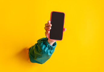 Female hand hold mobile phone on yellow background