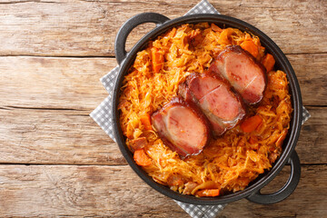 Baked Sauerkraut Podvarak with carrot, onion, smoked pork and bacon closeup in the pan on the table. horizontal top view from above