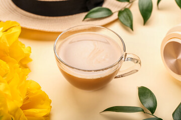 Cup of coffee with spring flowers on color background