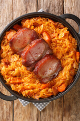 Podvarak Serbian Baked Sauerkraut with smoked meat closeup in the pan on the table. Vertical top view from above