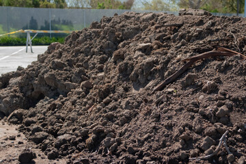Large pile of digged soil at the construction site on the parking lot, horizontal, copy space.