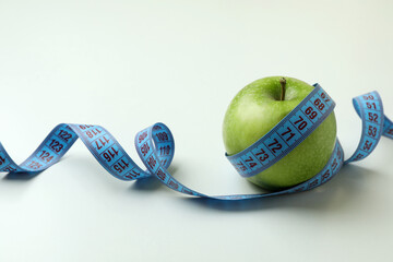 Green apple with measuring tape on white background