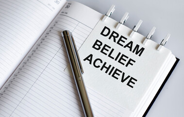 text DREAM BELIEF ACHIEVE on the short note texture background with pen. Business concept