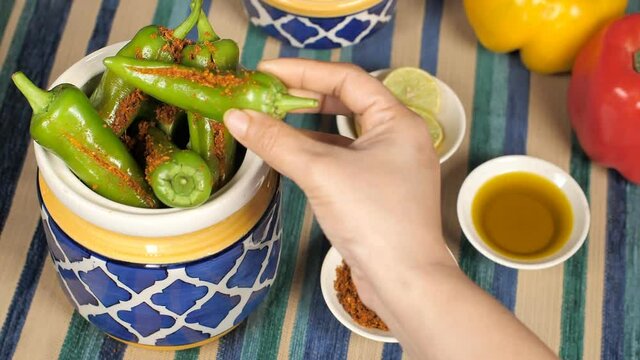 Masala stuffed / Bharwa green pickled chili - spicy tasty mirch ka achaar. Closeup shot of a bowl of lemon slices  Masala  mustard oil  and bell peppers kept on a table