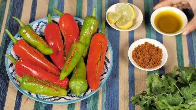 Rajasthani Mirchi Ka Achaar / stuffed chili pickle placed on a colorful background. Indian spicy green and red chilies Achaar with its stuffing Masala  lemon  and fresh coriander leaves on a table mat