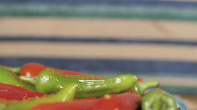 Delicious spicy stuffed chilies pickle made in India . Extreme close up shot of red and green plump big Mirchi stuffed with Masala with stems rotating on a plate
