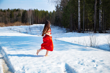 Photo of barefoot girl in a red dress walking on snow