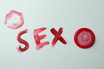 Sex made of lipstick and condom on white background