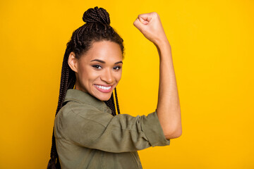 Photo portrait of african american girl flexing biceps isolated on vivid yellow colored background - obrazy, fototapety, plakaty