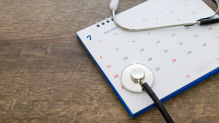 Stethoscope with date on calendar page on wooden table background doctor appointed health concept.