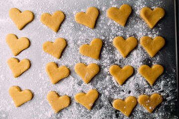 Top view on semi finished heart shaped cookies with flour