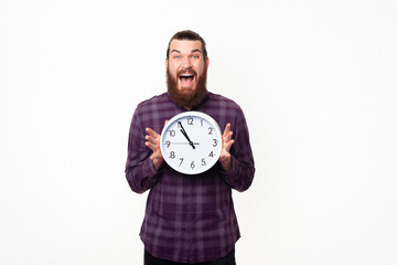 Amazed screaming young bearded man in casual showing white clock