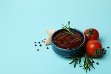 Bowl of barbecue sauce and spices on blue background