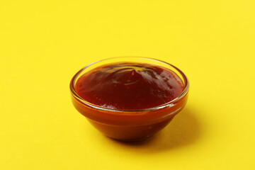 Bowl of barbecue sauce on yellow background
