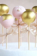 The pastry chef decorates cake pops with satin ribbons.Various cake pops decorated with white and dark chocolate on a brown background. High quality photo.