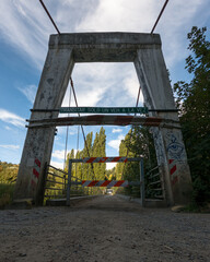 Beam metal suspension bridge on a sunny day in autumn.