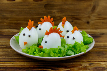 Funny easter breakfast with boiled eggs as chicks on wooden table