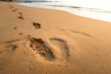 Fototapeta na wymiar Human's footprint mark on sand beach. Travel and relaxation concept background photo. Selective soft focus at footprint part.