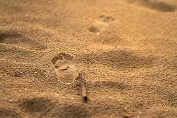 Human's footprint mark on sand beach. Travel and relaxation concept background photo. Selective soft focus at footprint part.