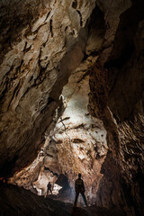 Fototapeta na wymiar Speleologists exploring a deep cave