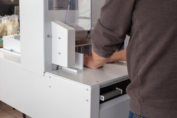the working operator works on an automatic machine for cutting a stack of papers or labels, a...