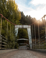 Beam metal suspension bridge on a sunny day in autumn.