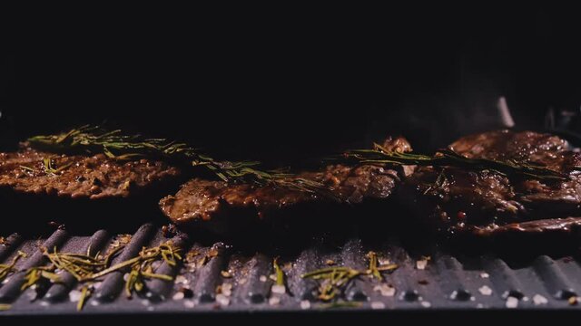 Delicious juicy meat steak cooking on grill. Prime beef fry on electric roaster, rosemary, black pepper, salt. Slow motion.