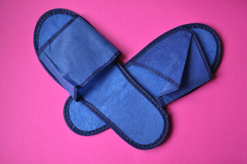 blue color textile travel disposable slippers isolated on a pink background close-up
