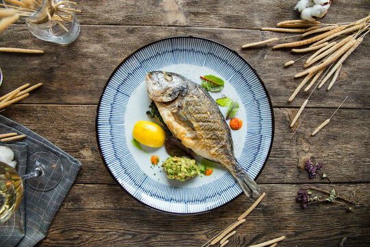 Top view on grilled dorada fish on the wooden background