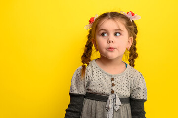Beautiful little girl on a yellow background in meditation dreams of the future.