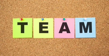 Color notes with letters pinned on a board. Word TEAM.