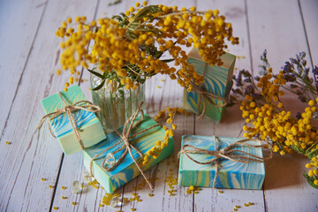 Fototapeta premium Colorful handmade scented soap and bright yellow acacia flowers on the wooden countertop.