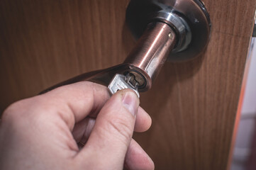 A man's hand opens an internal wooden door with a key