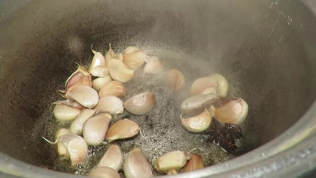 Putting handful of garlic cloves  into pot
