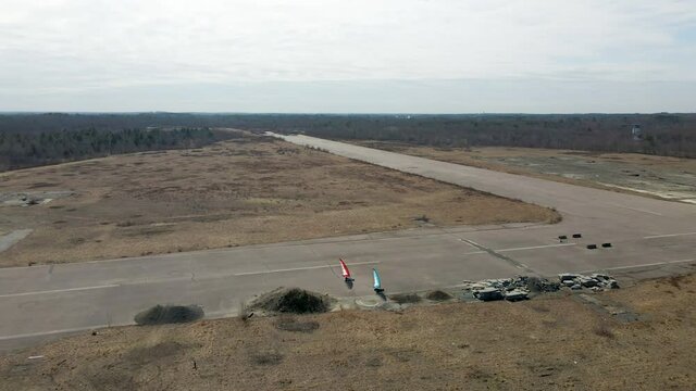 High drone footage of two land yachts turning on disused airfield.  South Weymouth Naval Base.  Aerial Static