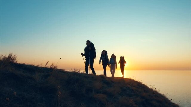The four travelers walking on the mountain top near the sea. slow motion