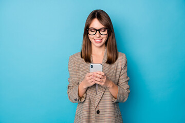 Photo portrait of cheerful woman holding phone in two hands isolated on vivid blue colored background