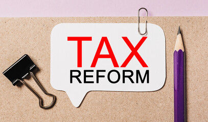Text tax reform on a white sticker with office stationery background. Flat lay on business, finance...