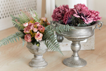 Bouquets artificial fabric roses in vases at the floor at home interior.