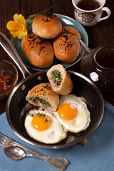 Hot homemade breakfast of scrambled eggs in a pan and baked pies with meat and onions