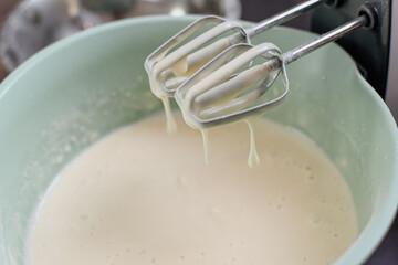 Dough preparation. Kneading the ingredients with a mixer in a container of light beige dough. Mixer blades