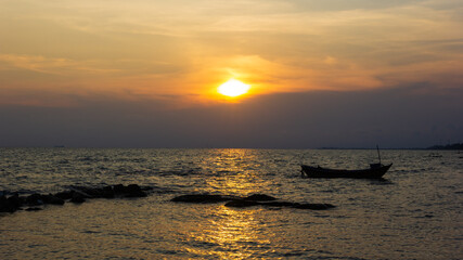 Silhouette of a fishing boat in the right of the picture, in the evening there is a sunset at the sea.