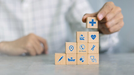 Hand arranging wood block with healthcare medical icon. Health insurance concept.