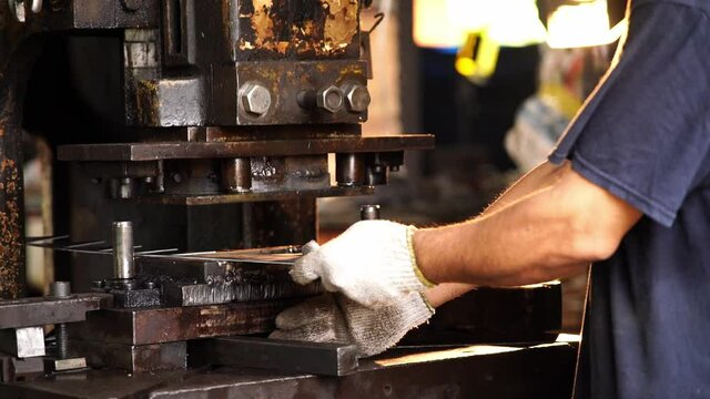 In the industrial plant A man is slowly cutting a sheet of metal or sheet with an old metal stamping machine.
A worker is cutting steel using a cutting machine. Cut to the desired shape.