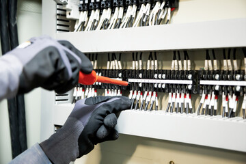 Electricians work to connect electric wires in the system, switchboard, electrical system in...
