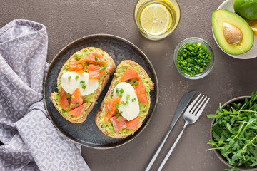 Delicious hearty breakfast, sandwiches with avocado paste, salmon and mozzarella on a plate, arugula and pea sprouts and green onion