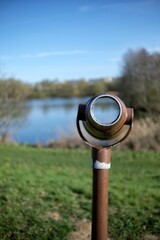 A single rusty  binocular out of order near a lake in France